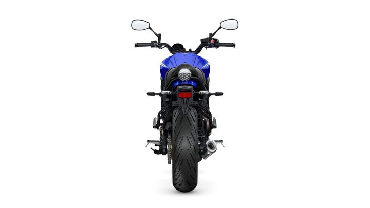 A rear view of a blue motorcycle featuring a large rear tire, a sleek tail light, and handlebars with mirrors. The background is white, highlighting the motorcycle's design.