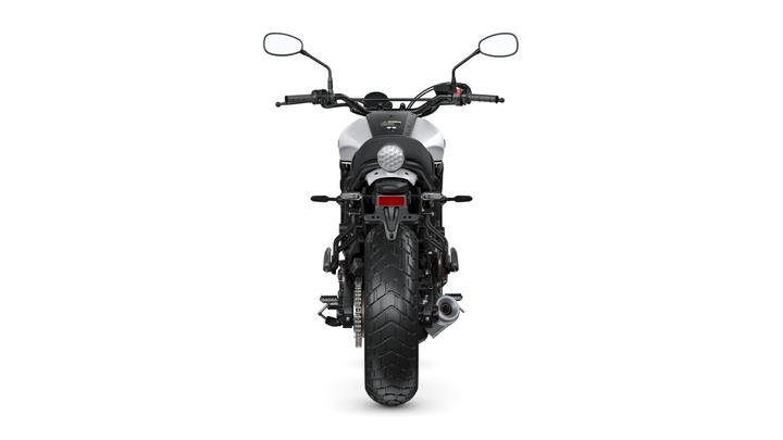 A rear view of a motorcycle showcasing its tire, exhaust, and taillight against a plain white background.