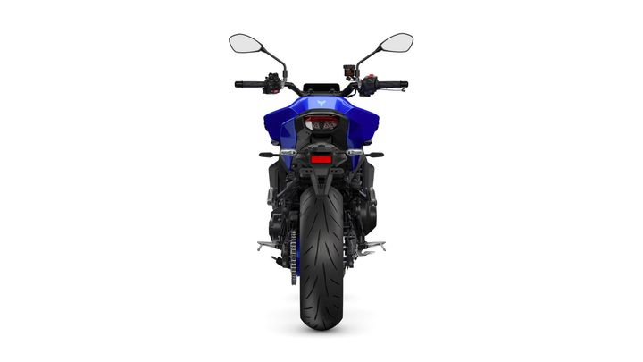A blue motorcycle viewed from the rear, showcasing its tail light, exhaust, and large rear tire against a white background.