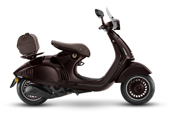 Vespa 946 Horse 125 Euro 5+ A glossy dark brown scooter with a retro design, featuring a brown seat and a small matching backpack attached to the rear. The scooter has a clear windshield and stylish wheels.
