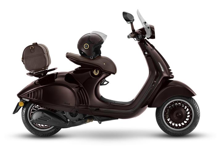 A glossy dark brown scooter with a sleek design, featuring a brown helmet resting on the seat and a matching brown backpack attached to the rear. The scooter has distinctive curves and modern details, set against a plain white background.