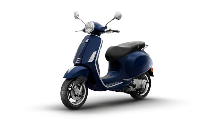 A navy blue scooter with a vintage design, featuring a rounded front, chrome mirrors, and a black seat, positioned on a white background.