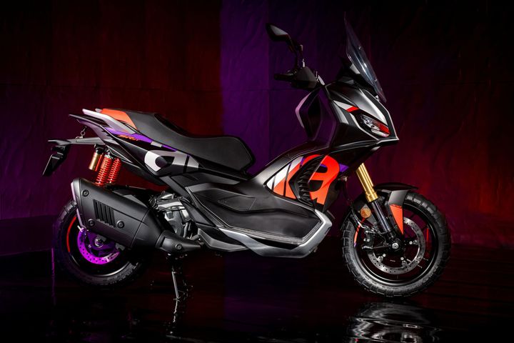 Aprilia SR GT 400 Rally Replica A sleek, modern scooter in black and orange, featuring a sporty design with a prominent front headlight, a high windshield, and distinctive color accents, set against a dramatic purple and red backdrop.