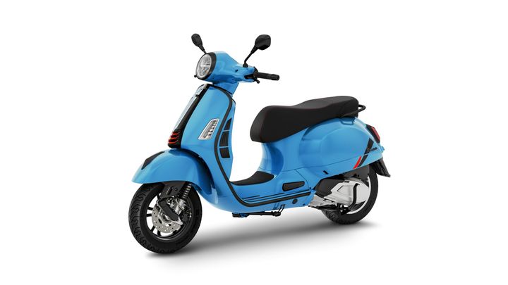 A bright blue scooter is displayed at an angle, showcasing its sleek design, black seat with red stitching, and detailed front headlight and handlebars.